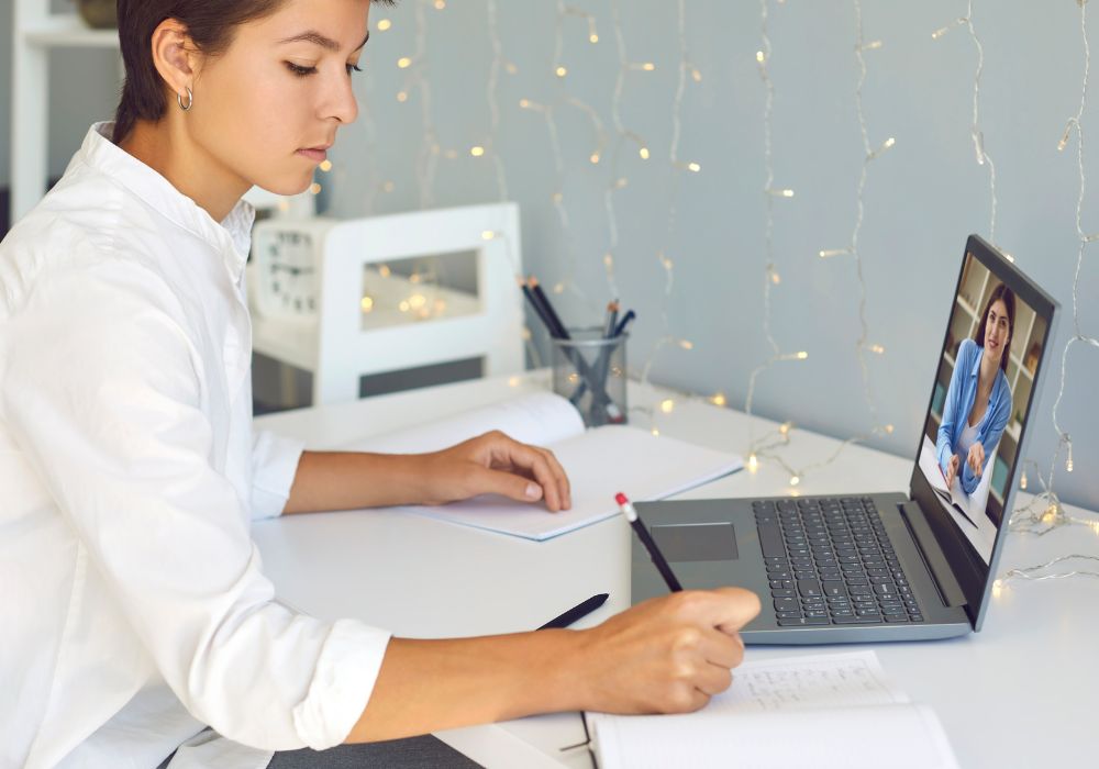 junge Frau am Laptop macht Notizen während einem online Coaching