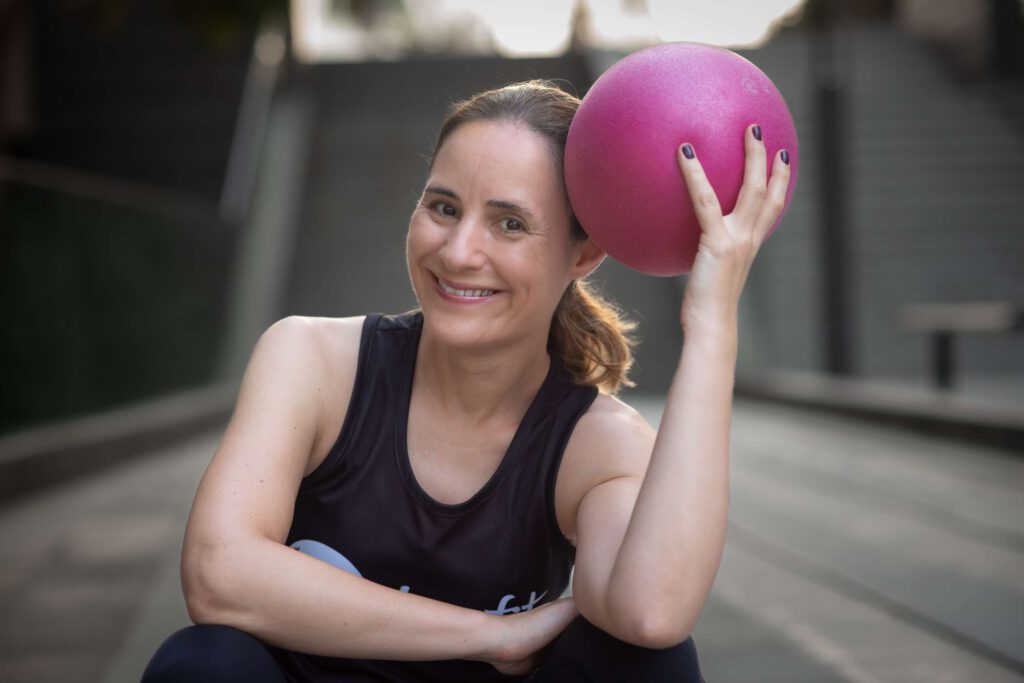 Eine Frau Haelt Draußen Einen Fitnessball Und Laechelt.