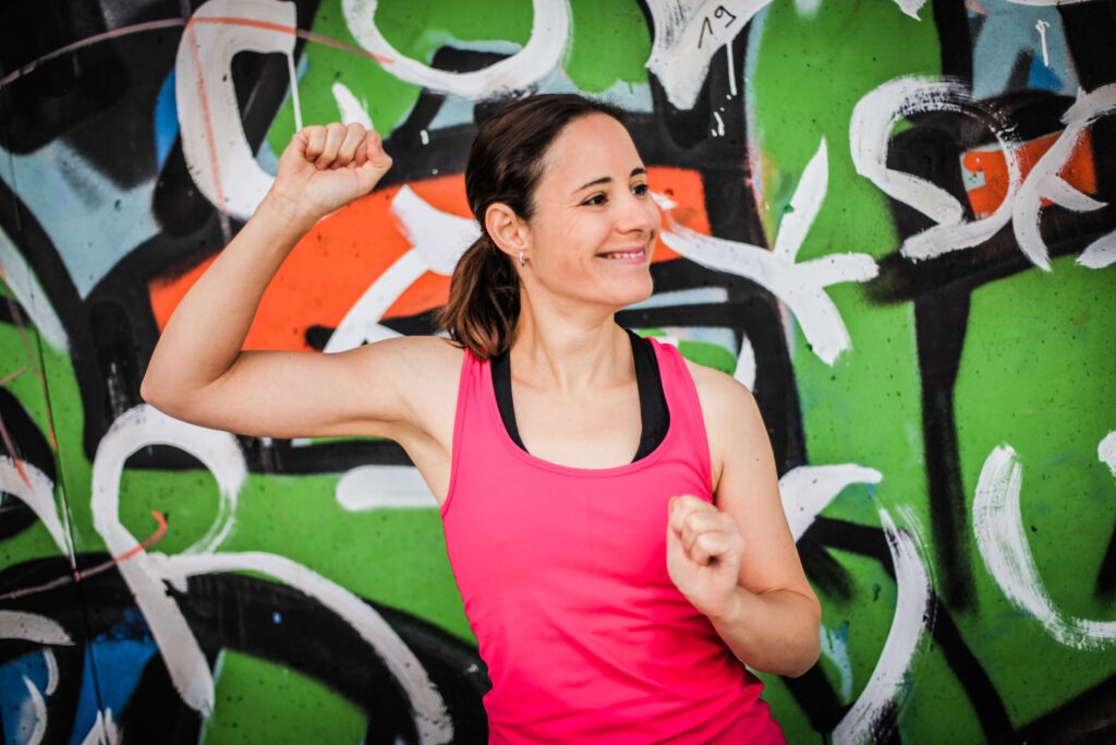 Eine Frau In Sportkleidung Posiert Vor Einer Bunten Graffitiwand.