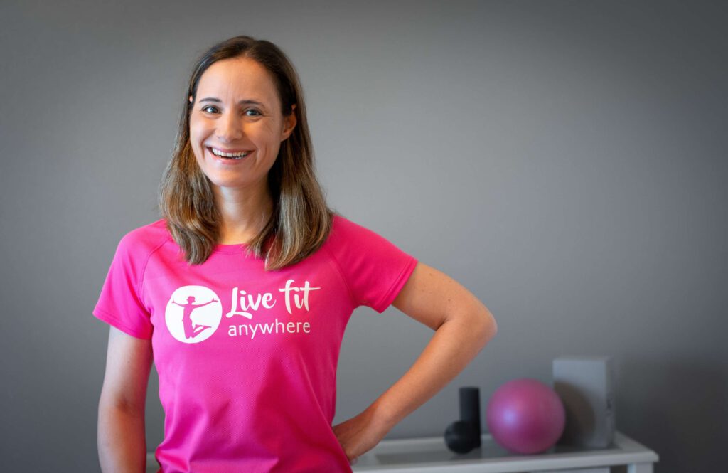 Frau In Einem Pinken T Shirt Steht In Einem Trainingsraum Und Laechelt.