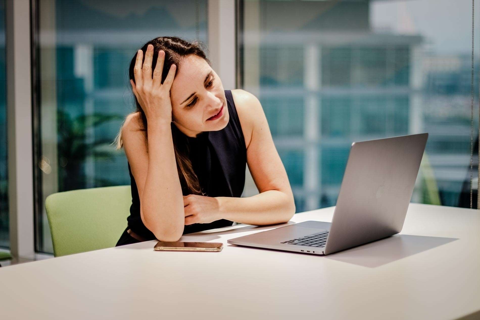 Eine Frau Sitzt Nachdenklich Vor Einem Laptop.