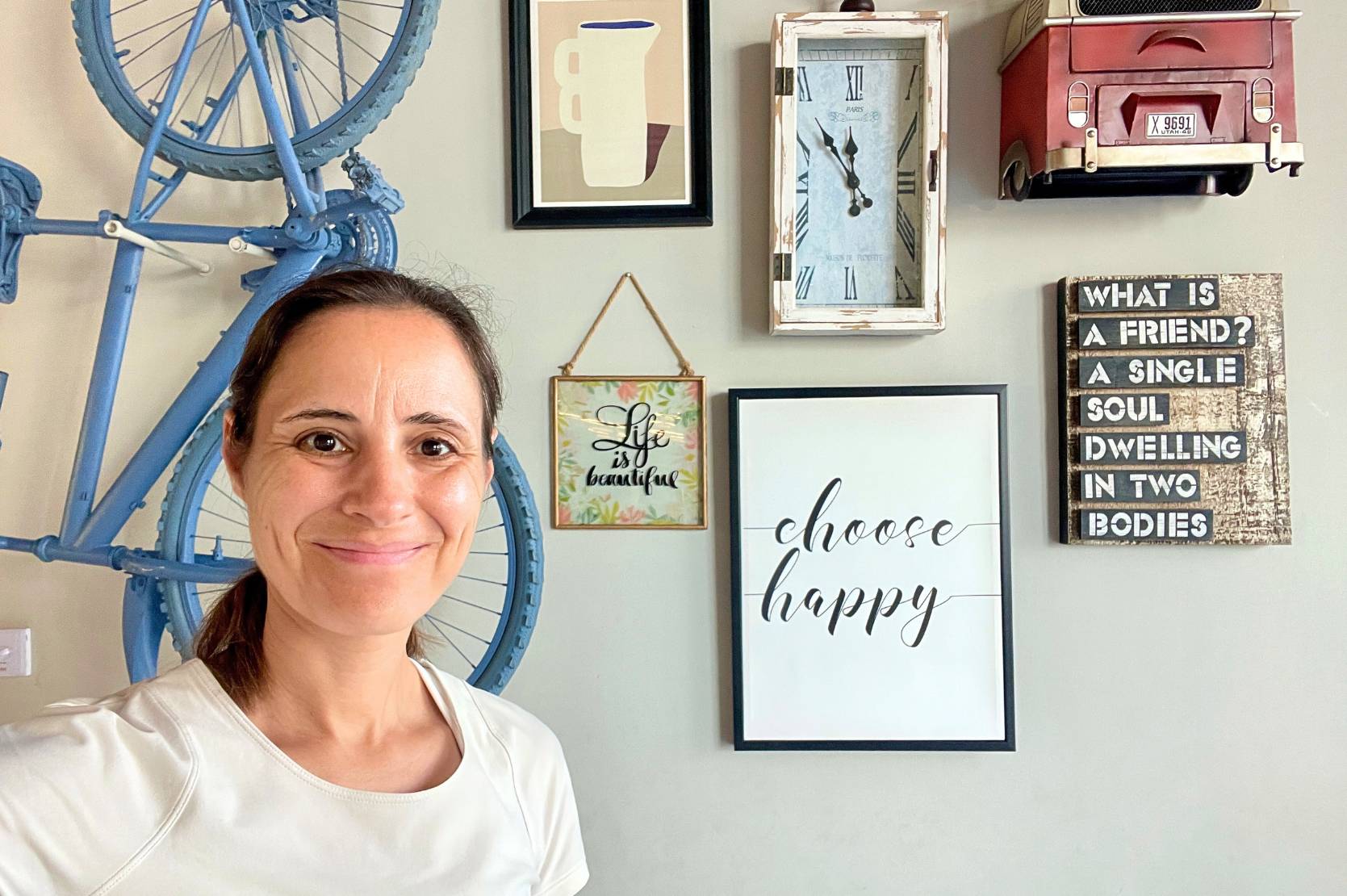 Lächelnde Frau steht vor einer Wand mit inspirierenden Bildern