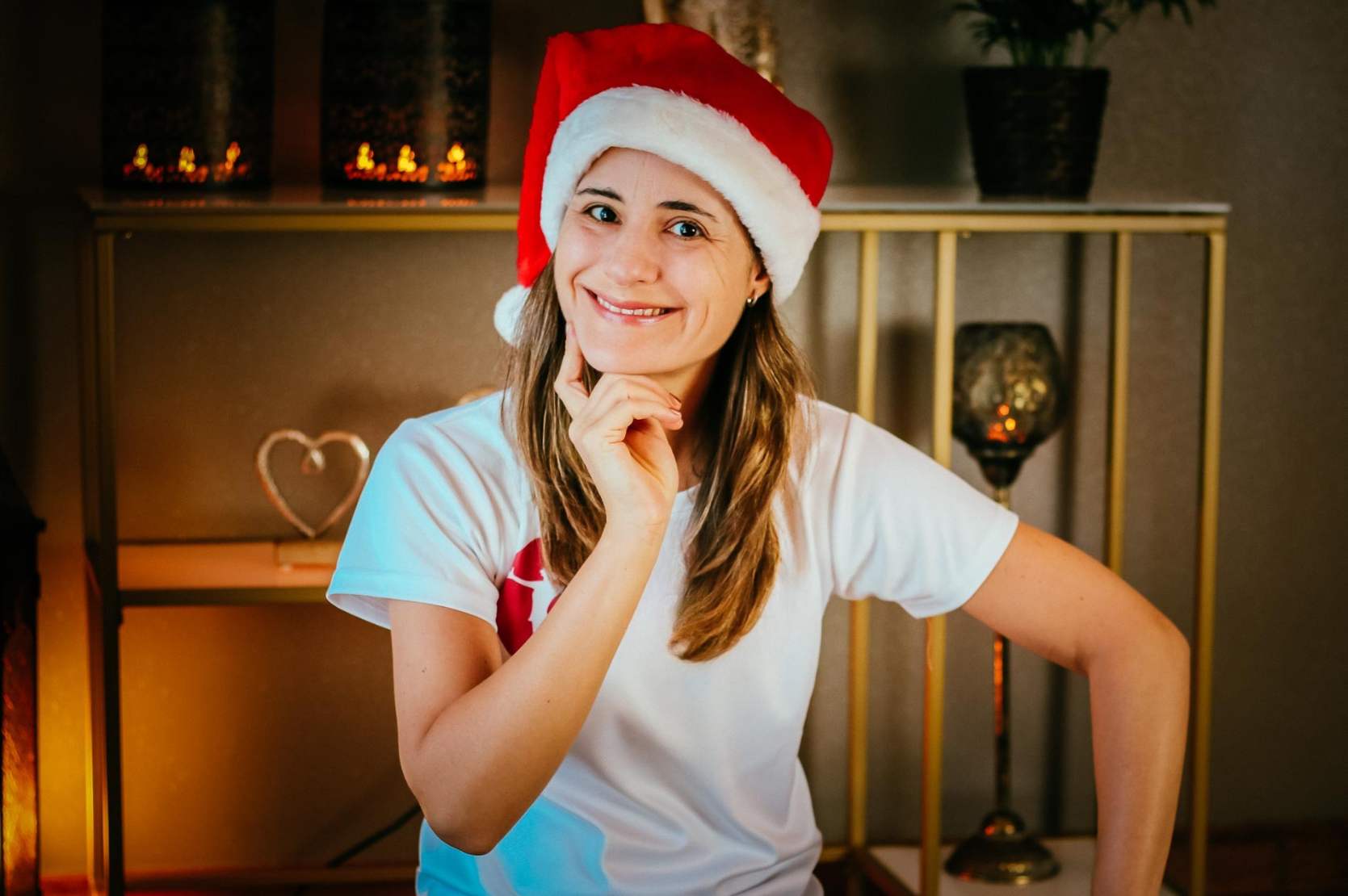 Frau mit Weihnachtsmütze sitzt vor gemütlichem Hintergrund