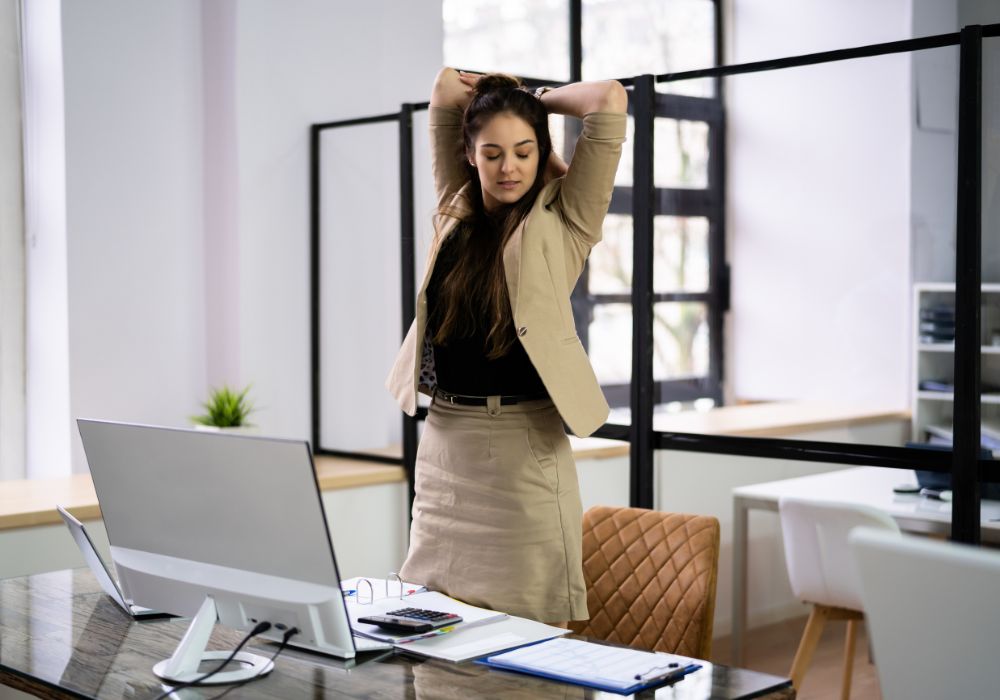 Business Frau dehnt sich im Stehen im Büro